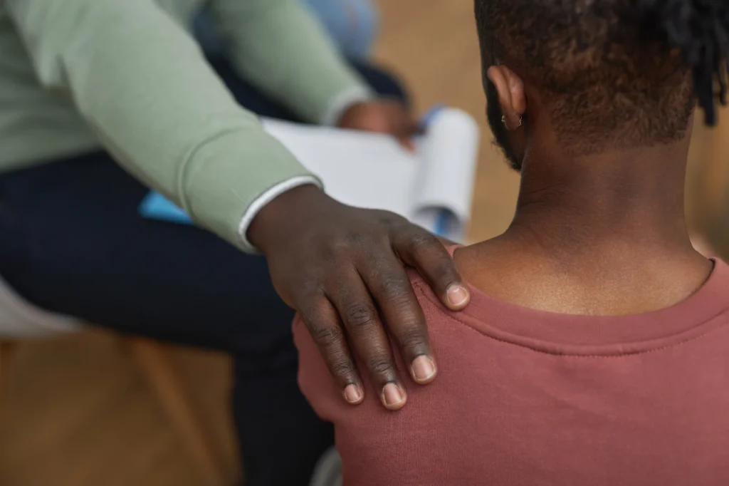 Man sitting with hand on shoulder